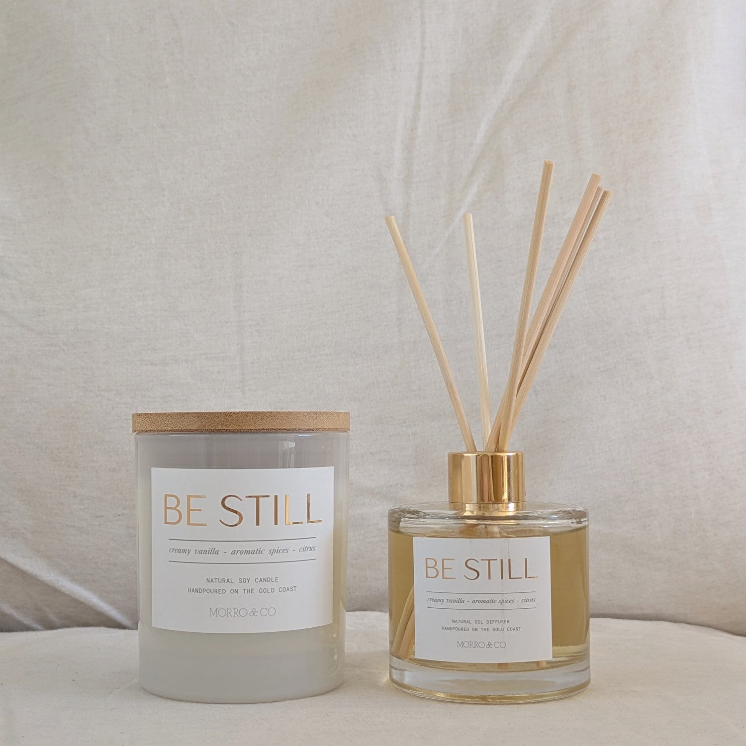 Candle and diffuser set with 'BE STILL' labels on a neutral background