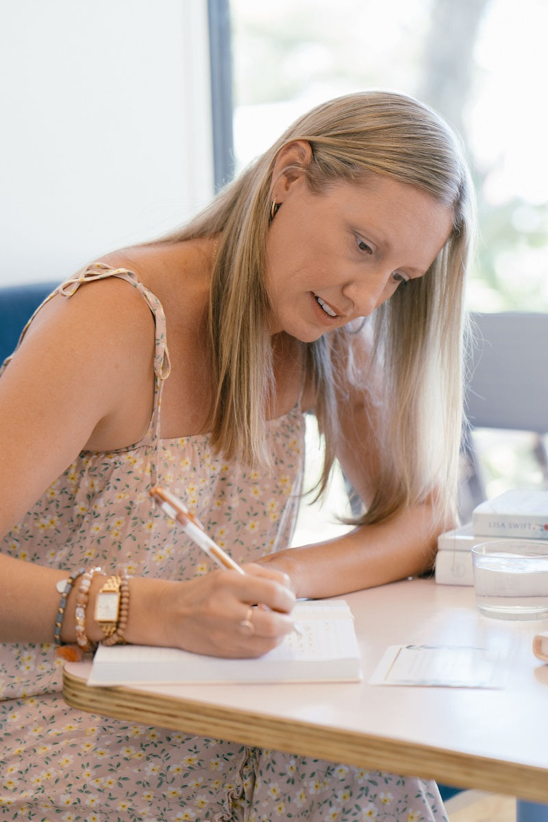 woman sitting by the window in a cafe writing in a journal