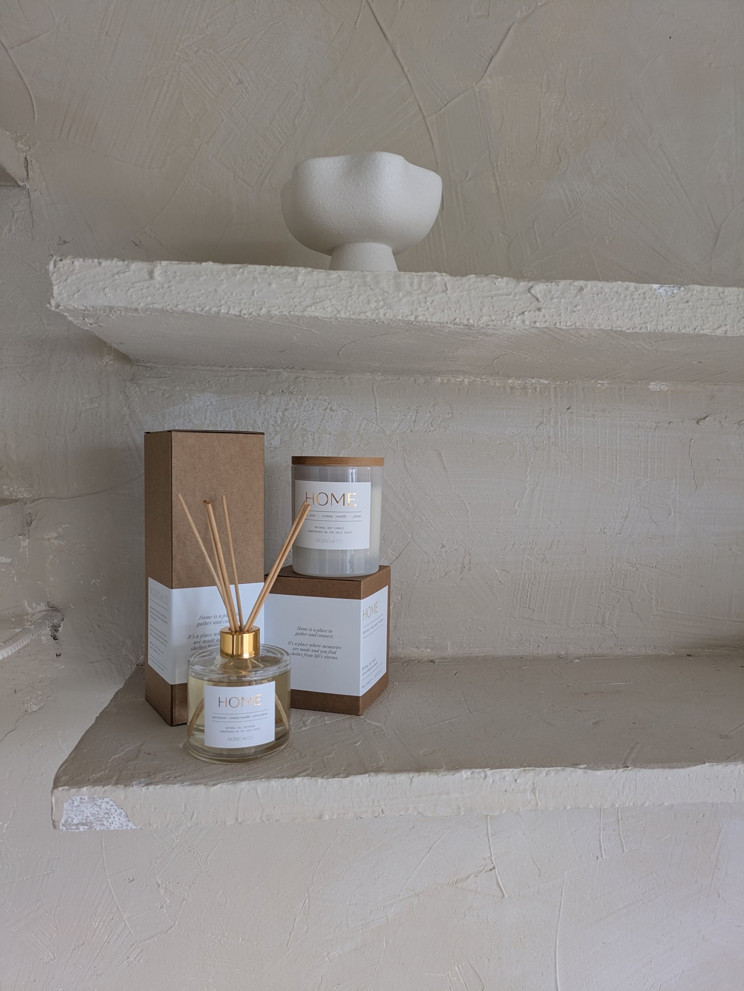 Two glass containers with gold accents on a stone shelf.