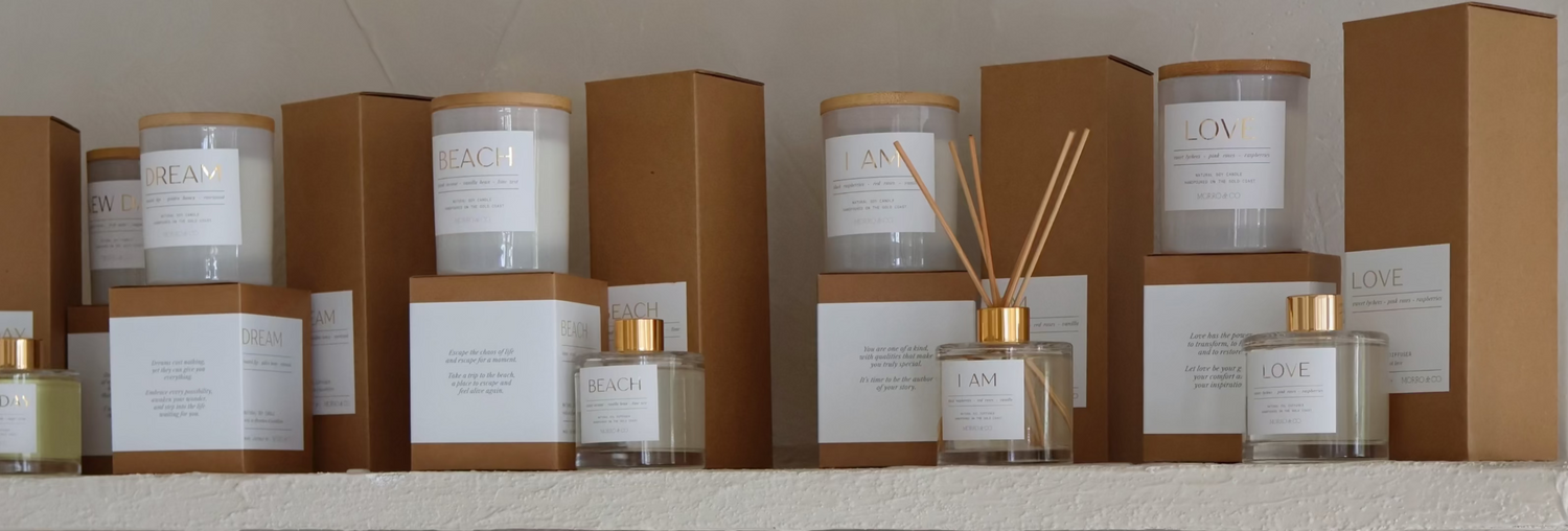 Display of candles and diffusers on a shelf with neutral packaging.
