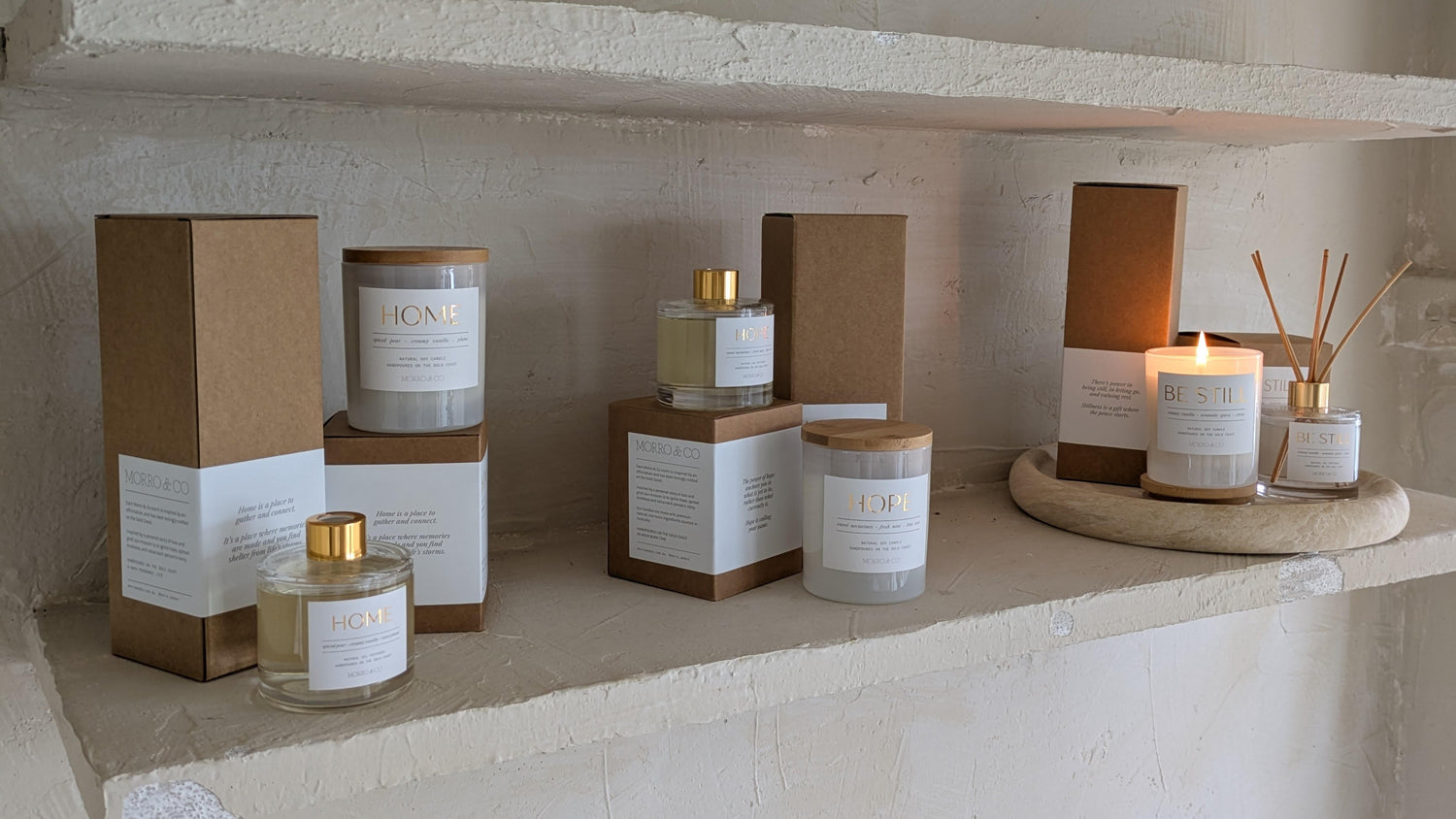 Candle and diffuser products on a stone shelf with a neutral background