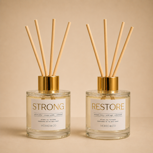 Morro & Co Two diffusers labeled 'STRONG' and 'RESTORE' with gold caps on a beige background.
