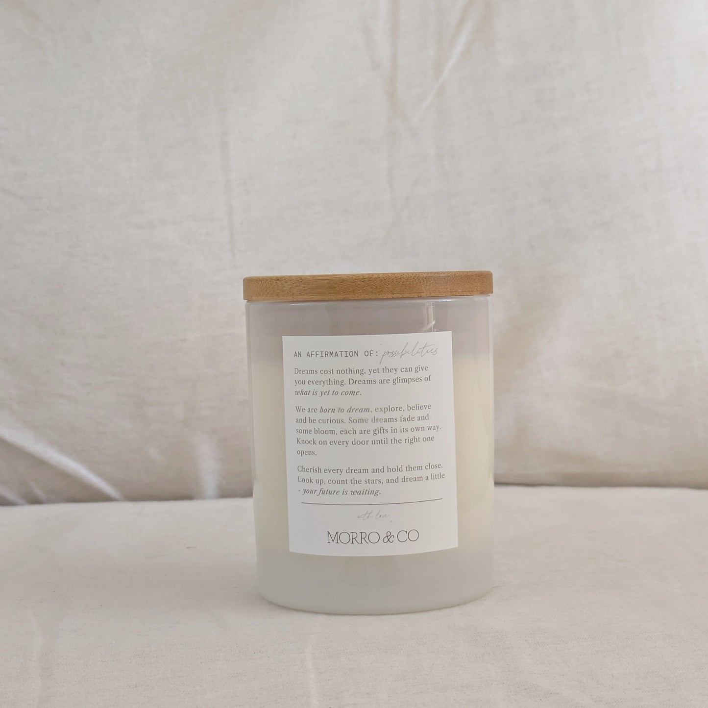 Back of DREAM candle with a wooden lid and affirmation label on a white background