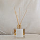 Reed diffuser with gold accents and positive affirmation on a neutral background