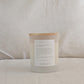 Back of LOVE candle with a wooden lid and an affirmation label on a neutral background