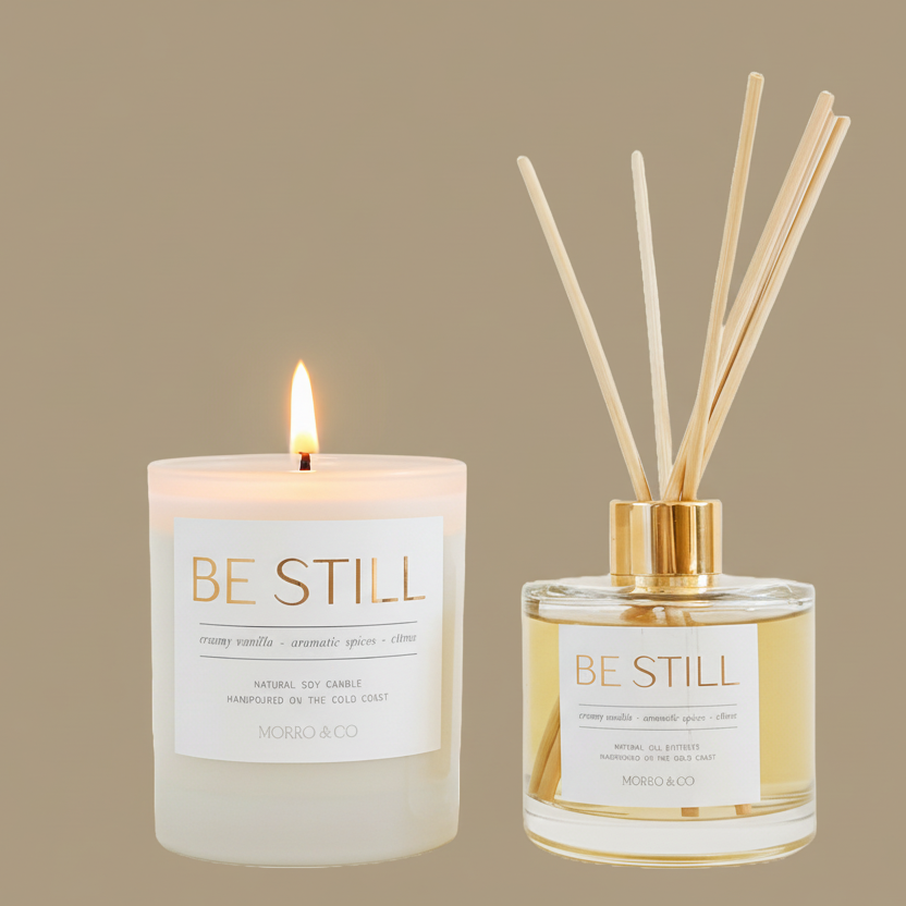 Candle and diffuser set with 'Be Still' label on a beige background