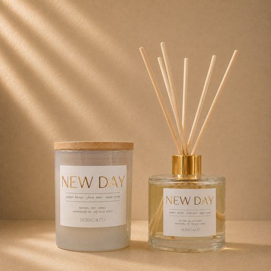 Morro & Co NEW DAY natural soy candle and eco reed diffuser on a warm beige background