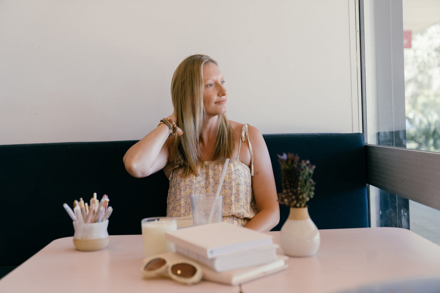 Woman sitting at a table with a notebook and glasses in a cafe.