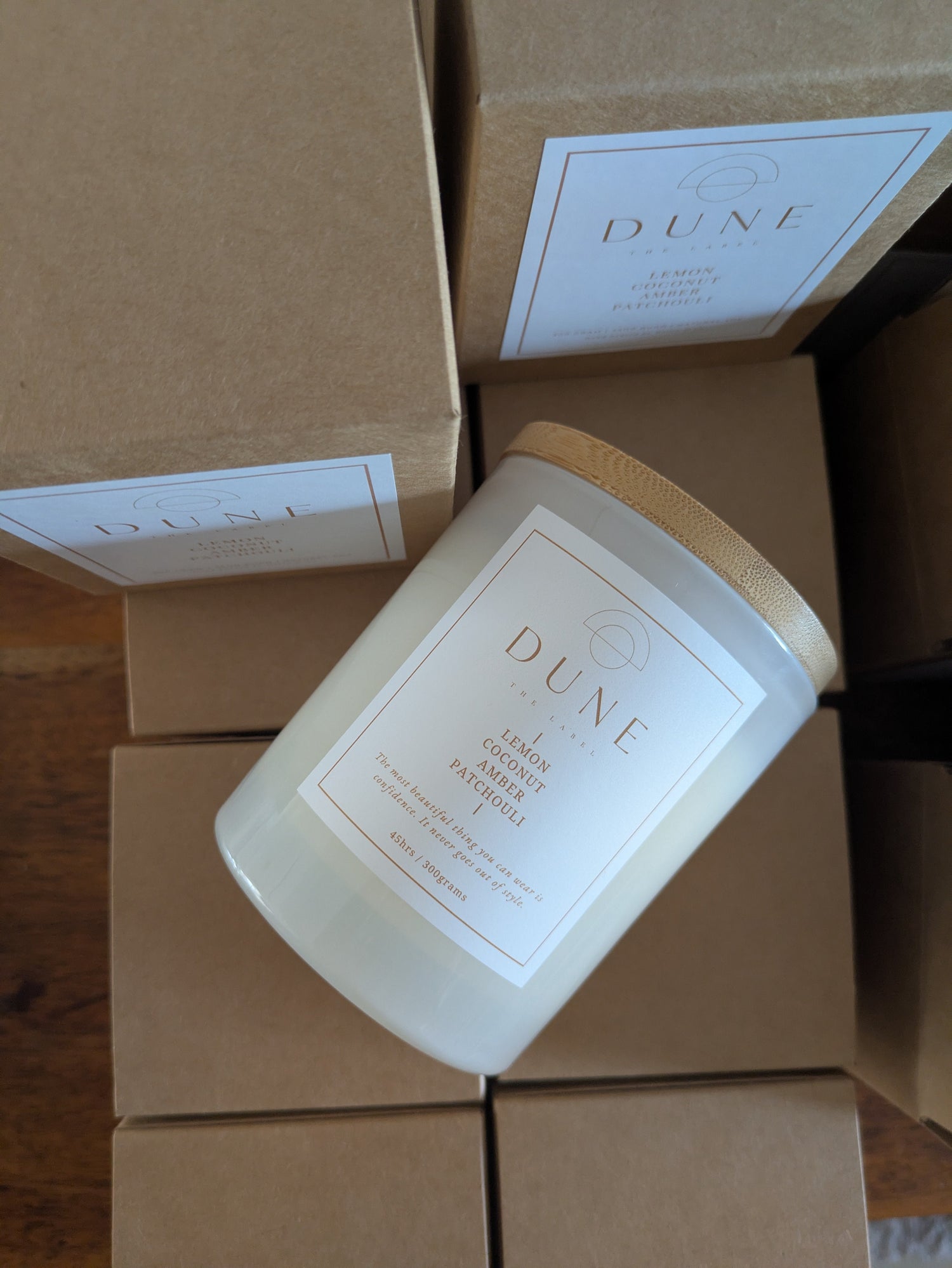 Candle with 'Dune' branding on a stack of brown boxes