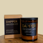 Dapper candle and packaging on a wooden surface with a beige background