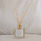 Eco Reed diffuser with wooden sticks in a clear bottle on a neutral background
