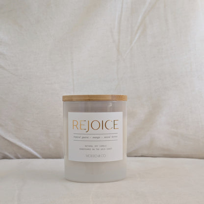 Front of REJOICE candle with 'REJOICE' label on a neutral background