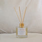 Eco reed diffuser with gold cap and 'STRONG' label on a neutral background