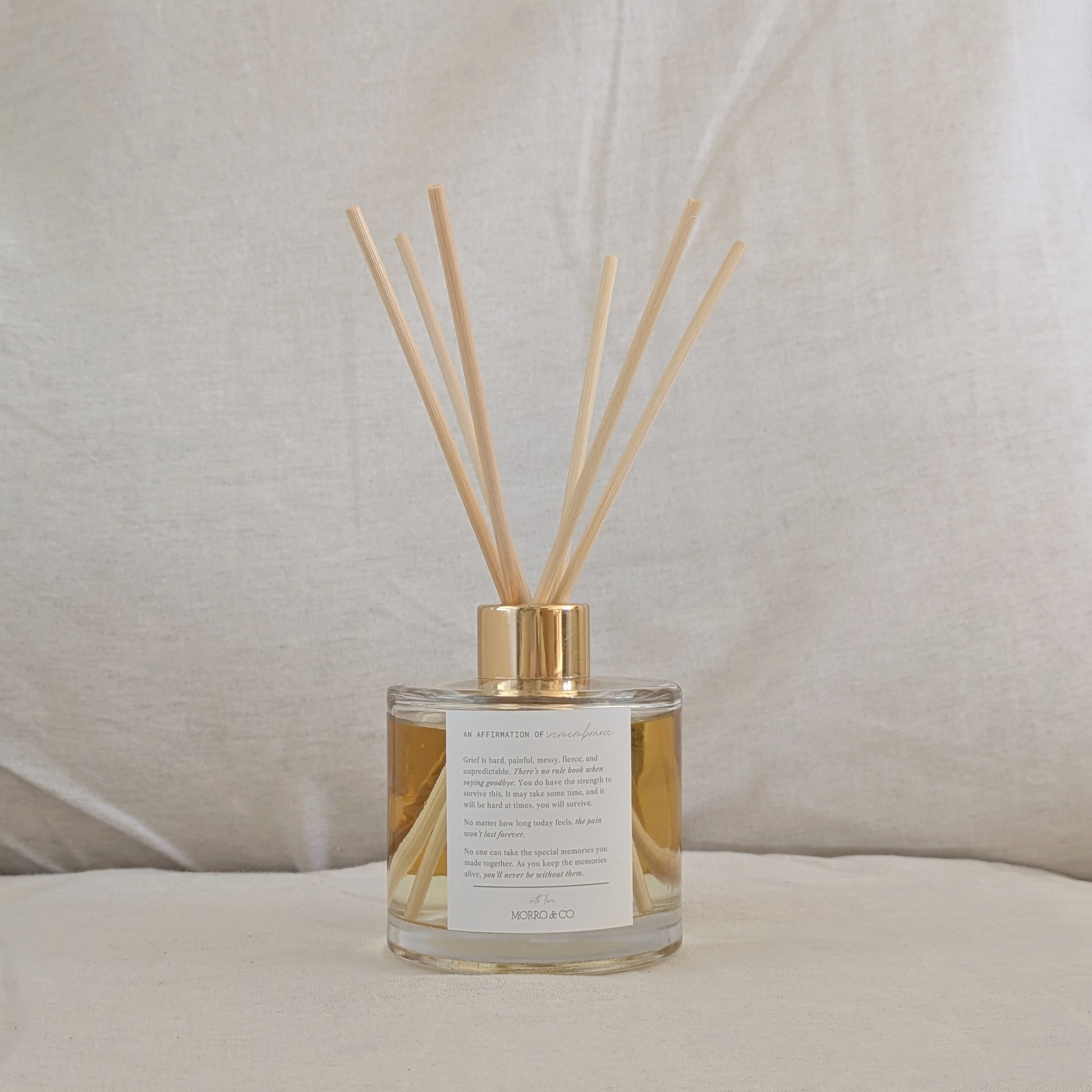Natural eco reed diffuser with wooden sticks in a glass bottle, affirmation label on a neutral background