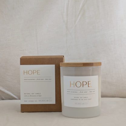 Candle and packaging with 'HOPE' label on a neutral background
