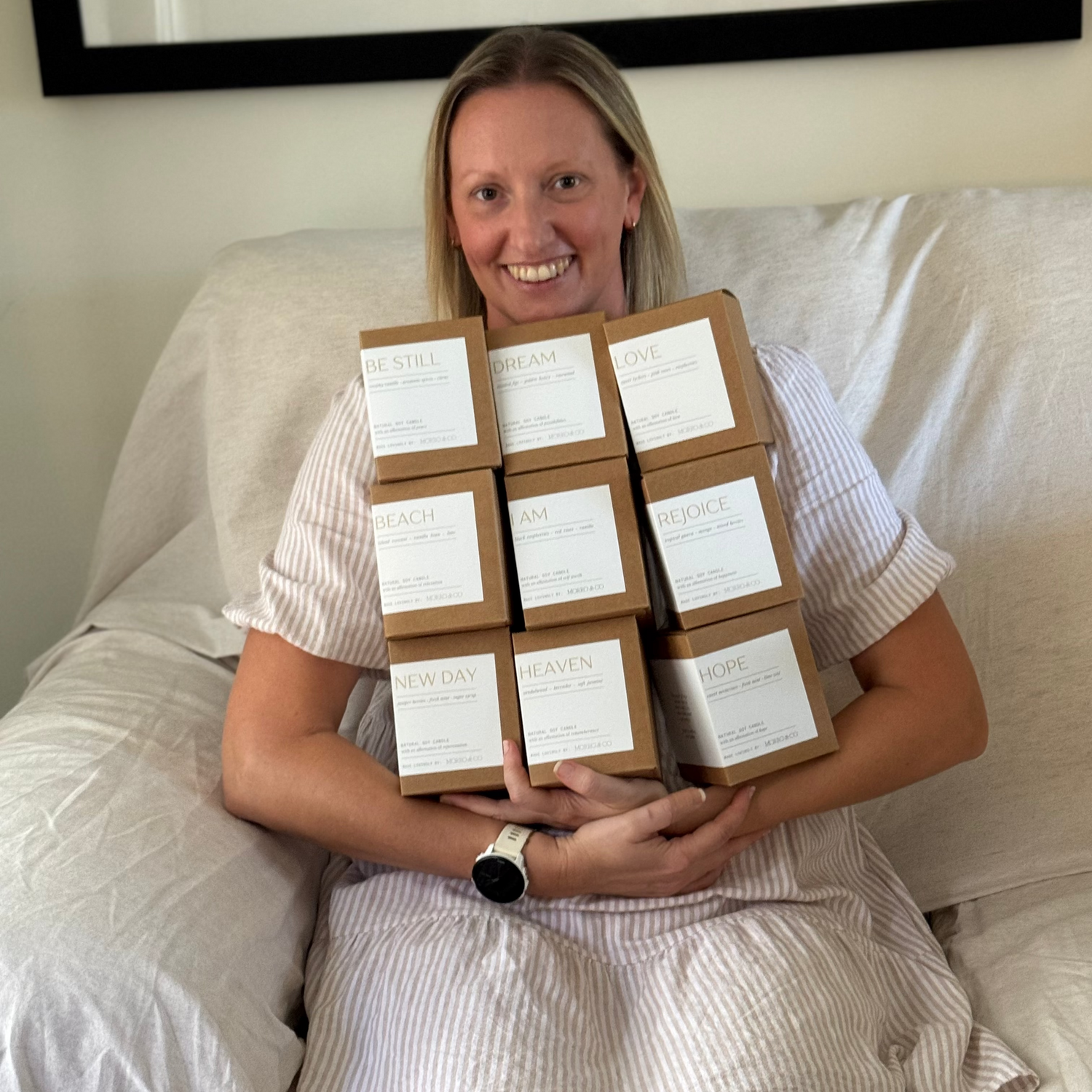 Woman sitting on a couch holding multiple boxes with labels.