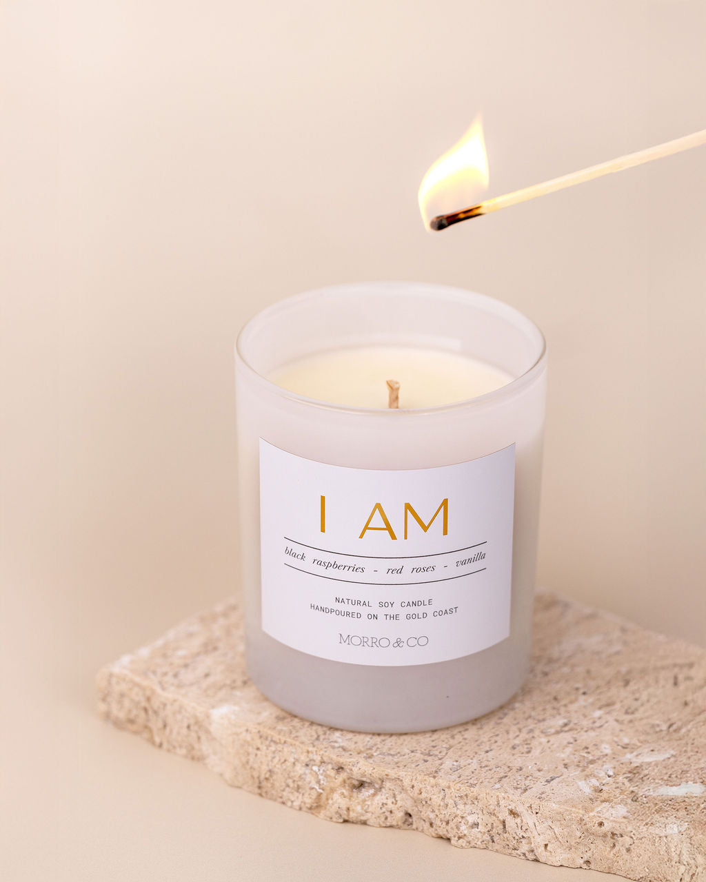 Candle labeled 'I AM' being lit with a match on a neutral background