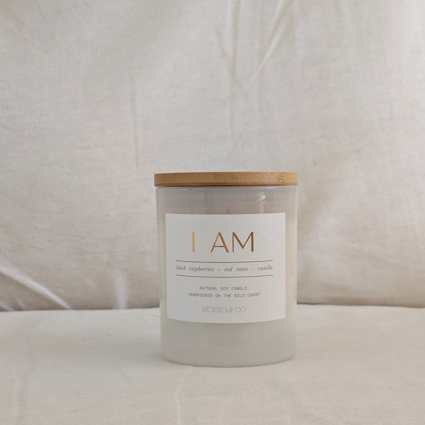 Candle with a wooden lid and white label on a beige background