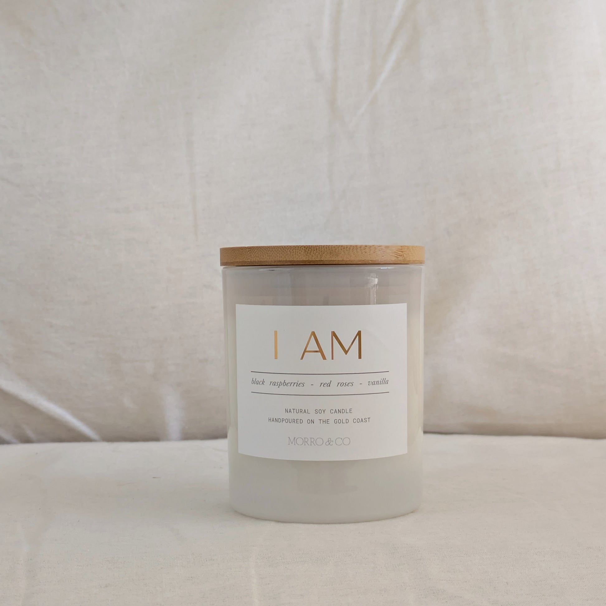 Candle with a wooden lid and white label on a beige background