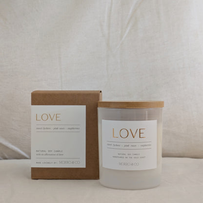 Candle and packaging with 'LOVE' label on a neutral background