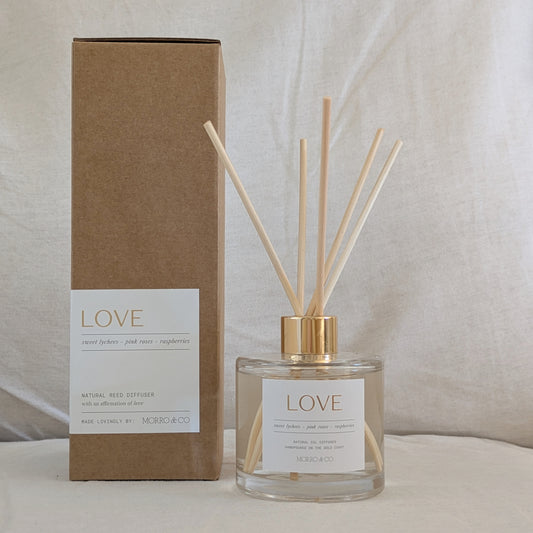 Reed diffuser with 'LOVE' packaging on a neutral background