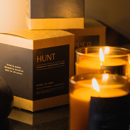 Candles and boxes with 'HUNT' branding in a warm, dimly lit setting.