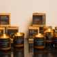 Collection of candles with labeled containers on a reflective surface.