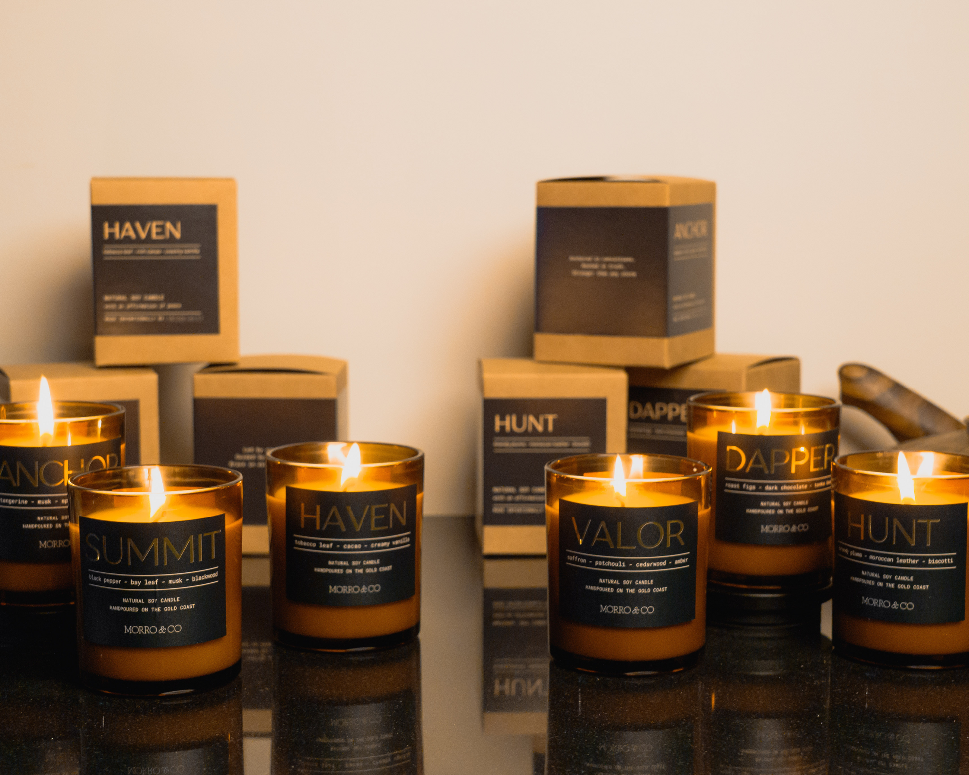 Collection of candles with labeled containers on a reflective surface.