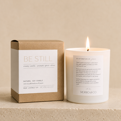 Candle with a box labeled 'Be Still' by Morro & Co on a beige background