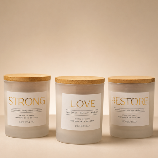 Three candles with labels 'Strong', 'Love', and 'Restore' on a beige background.