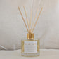 Natural eco reed diffuser labeled 'New Day' with wooden sticks on a neutral background