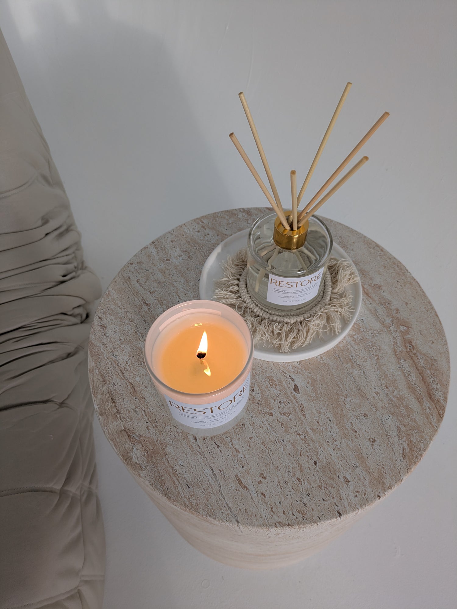 RESTORE candle and diffuser on a stone surface with a neutral background