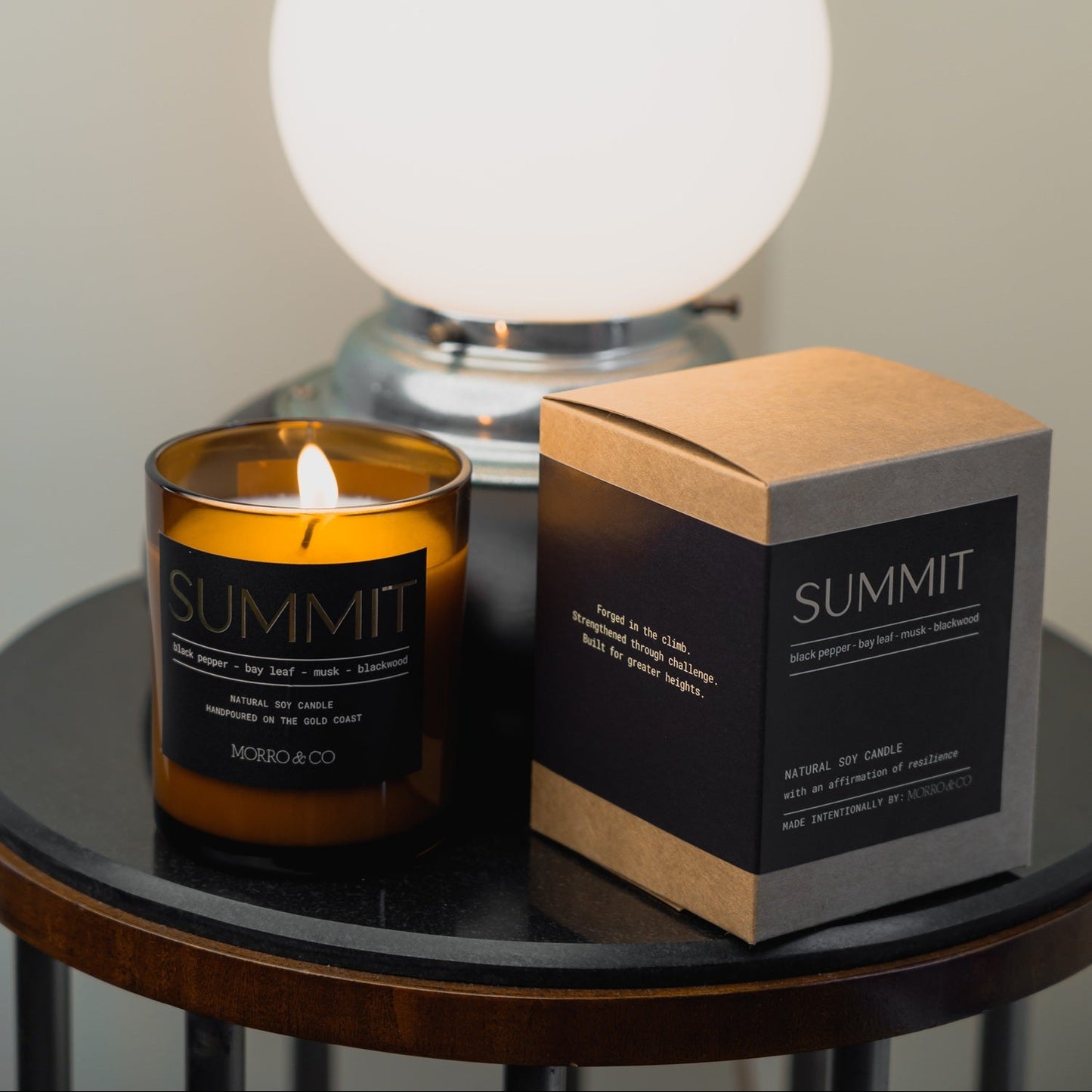 Morro & Co masculine candle labelled 'Summit' and packaging on a table with a spherical lamp in the background