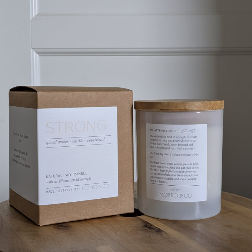 Candle and packaging on a wooden surface with a neutral background