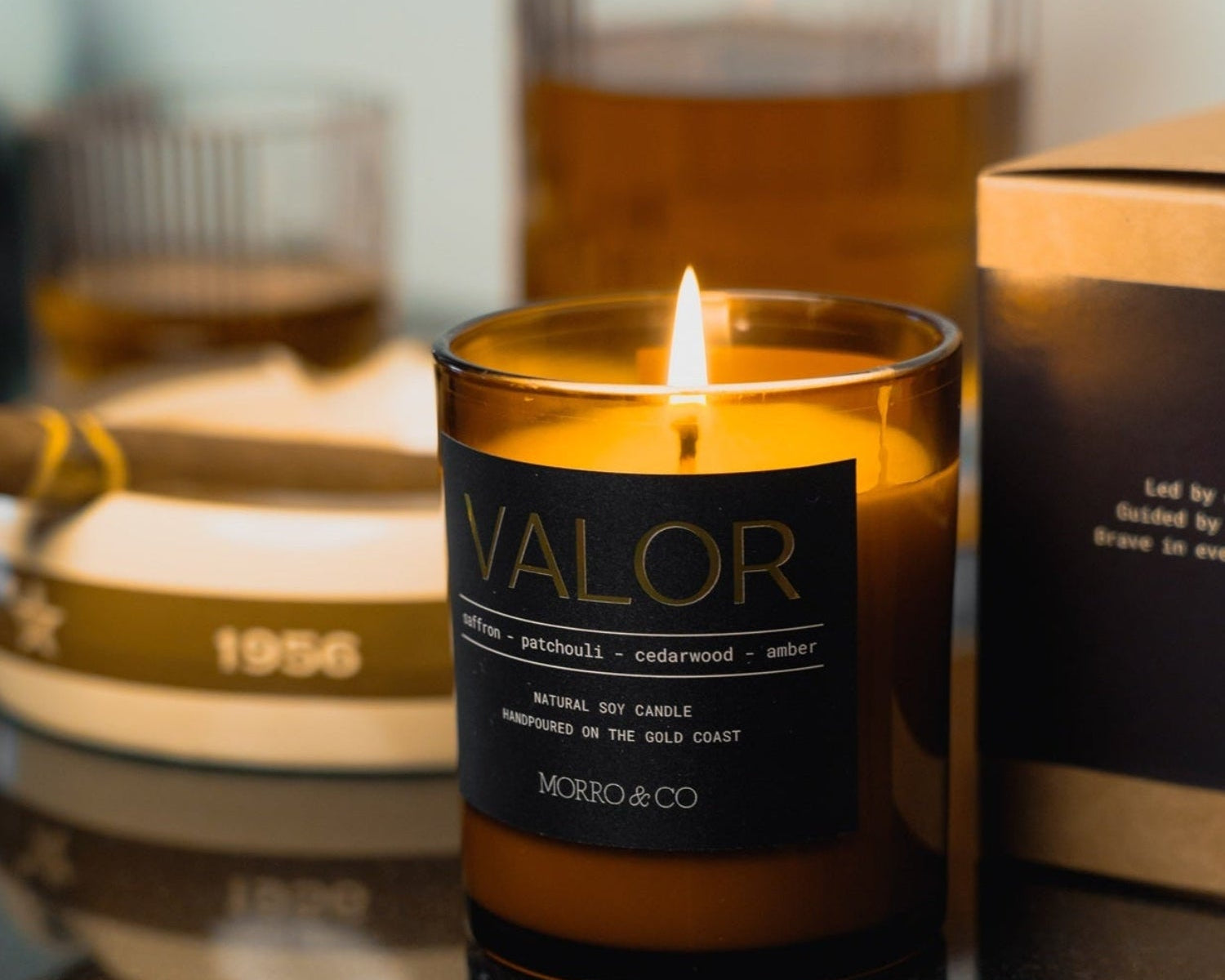 Morro & Co masculine candle labeled 'Valor' on a reflective surface with blurred background