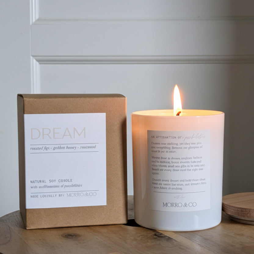 Candle and packaging labeled 'Dream' on a wooden surface with a neutral background