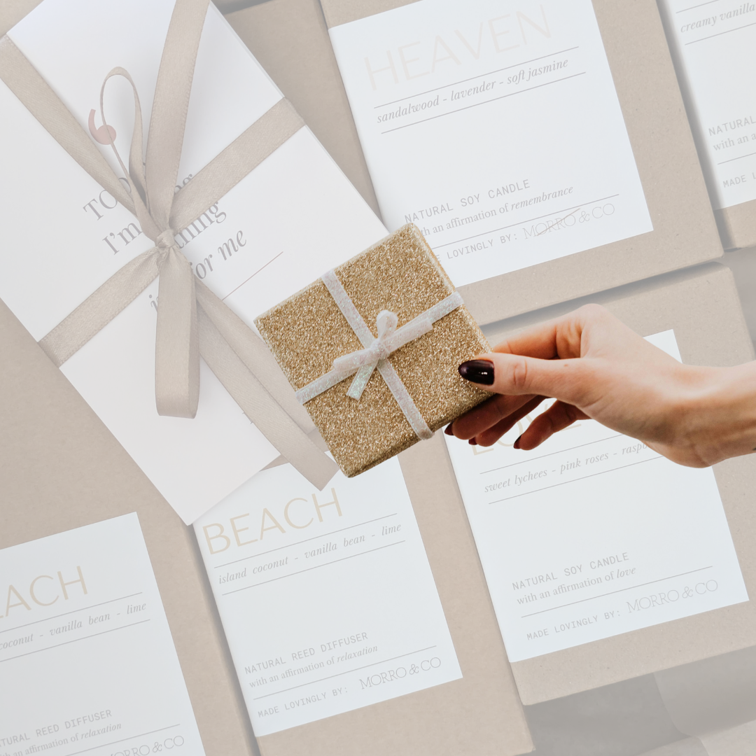 Hand holding a small glittery gift box over wedding invitations with 'Beach' text.