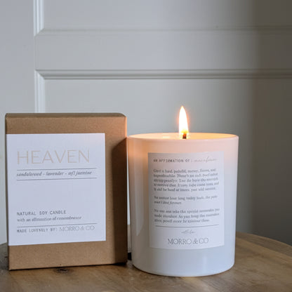 Candle and packaging labeled 'Heaven' on a wooden surface with a neutral background