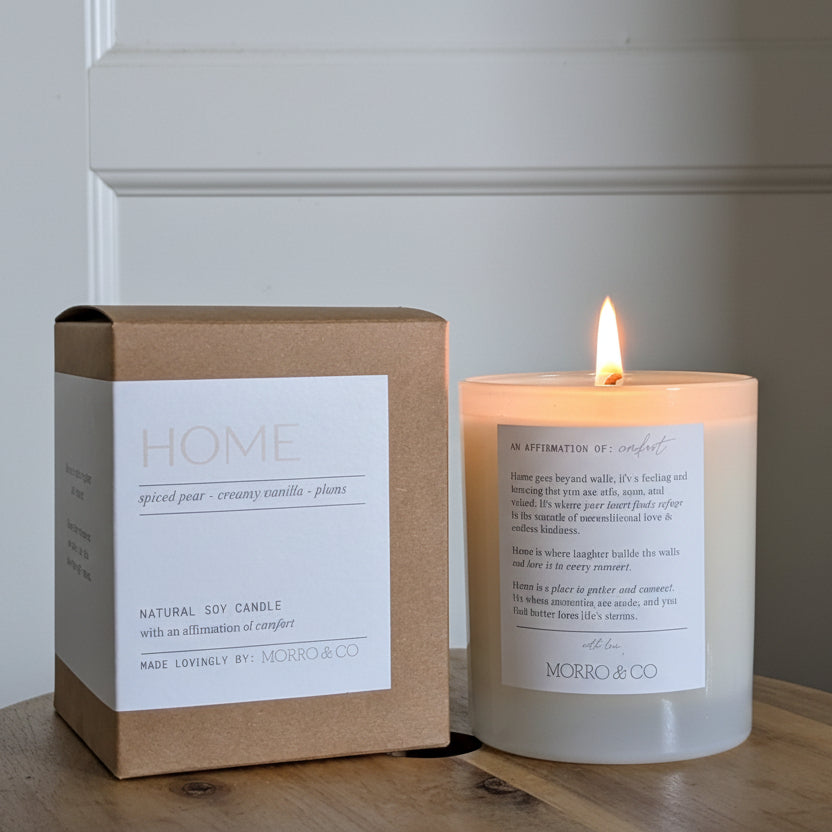Candle and packaging on a wooden surface with a neutral background
