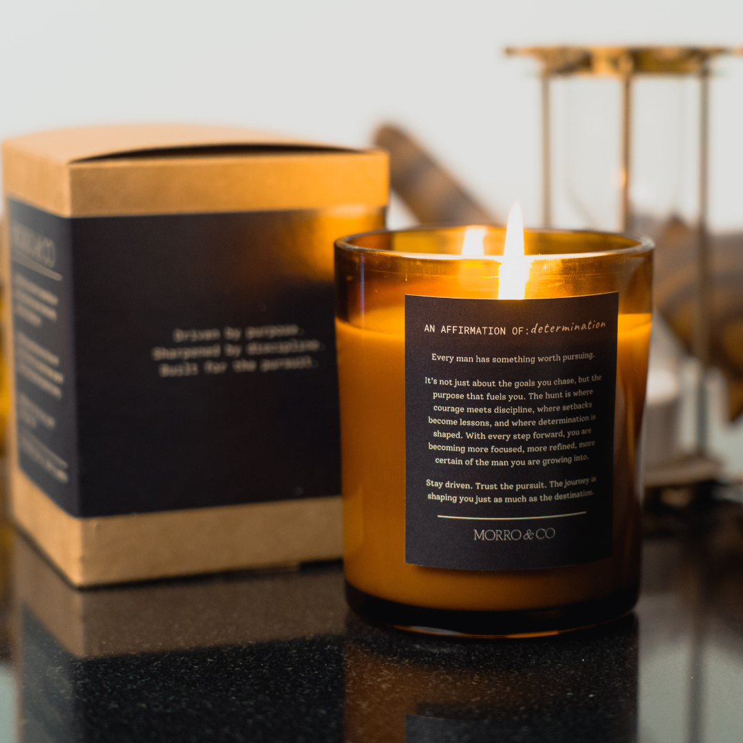 Candle with a label in front of a box on a reflective surface
