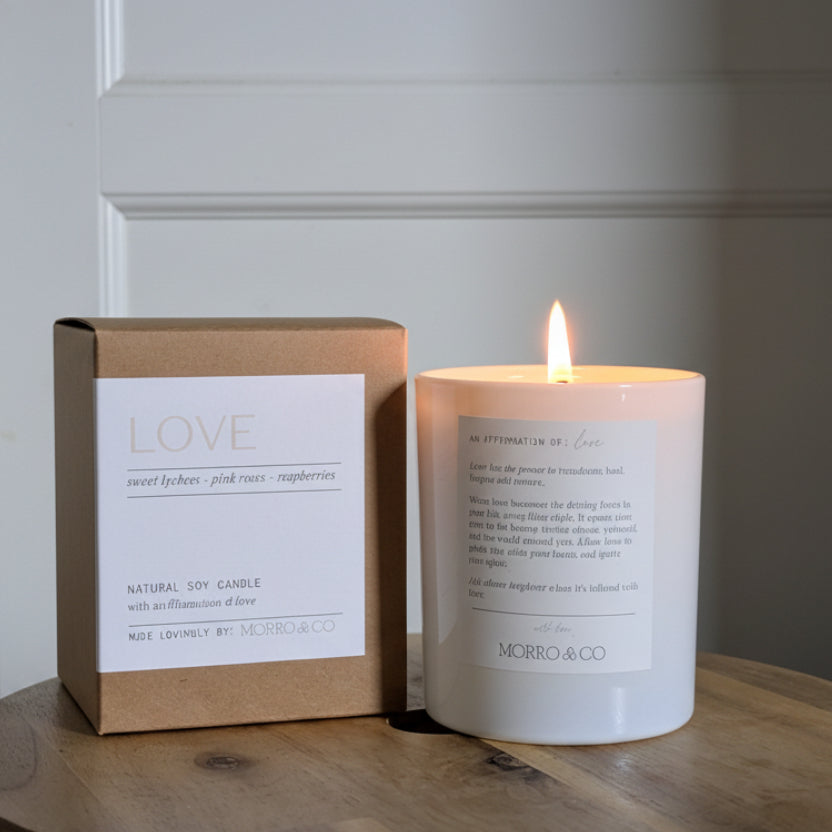 Candle and packaging on a wooden surface with a neutral background