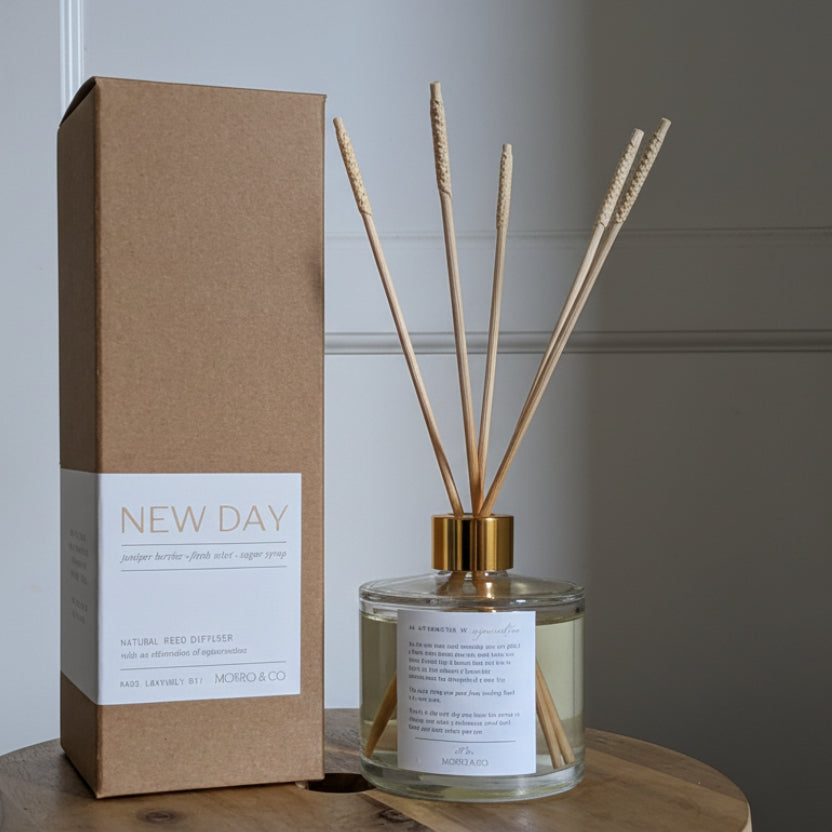 Diffuser bottle and packaging labeled 'New Day' on a wooden surface.