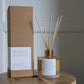 Diffuser bottle and packaging with 'Rejoice' branding on a wooden surface.