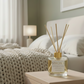 Reed diffuser on a nightstand next to a bed with a blanket