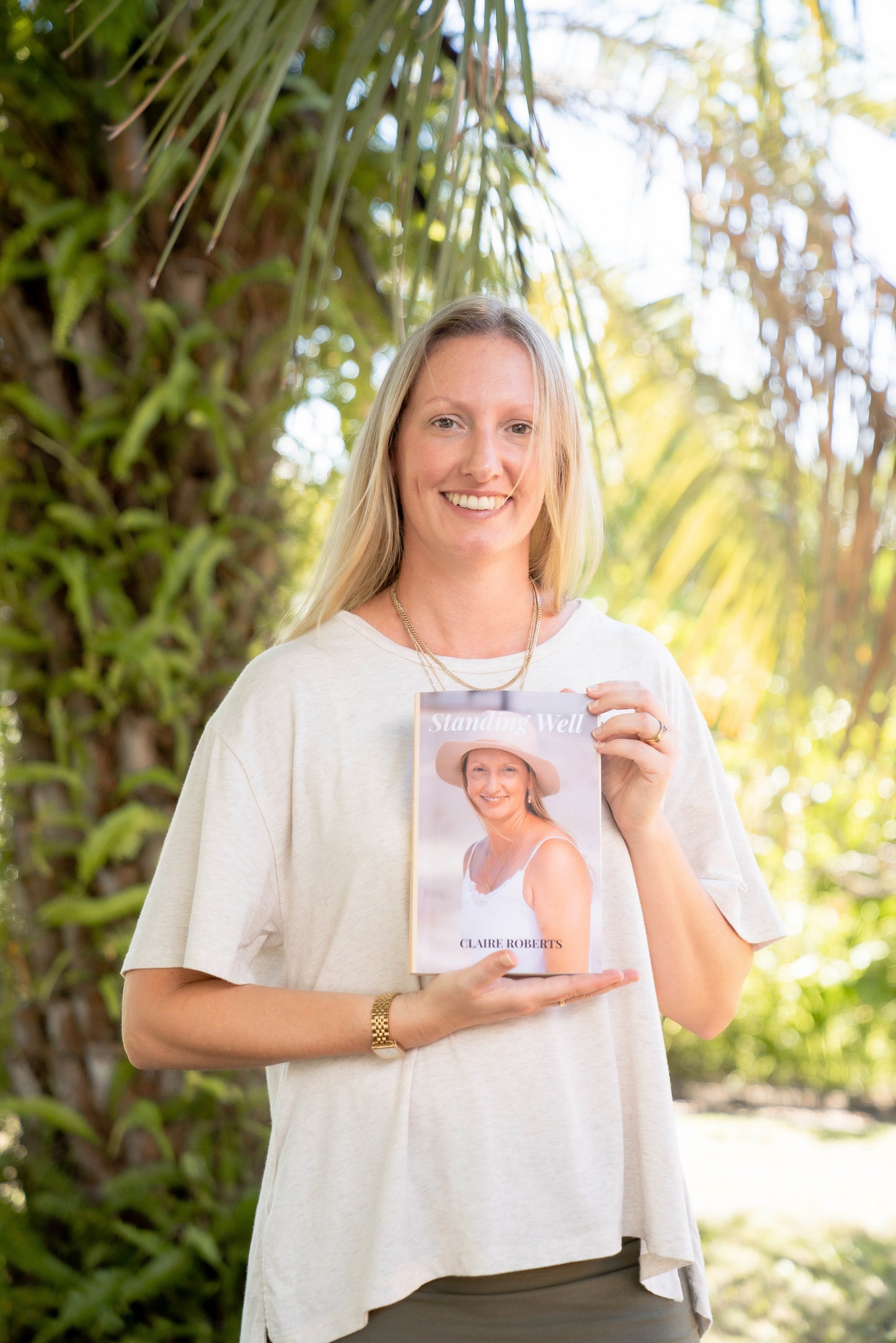 Woman standing in a garden holding her published book